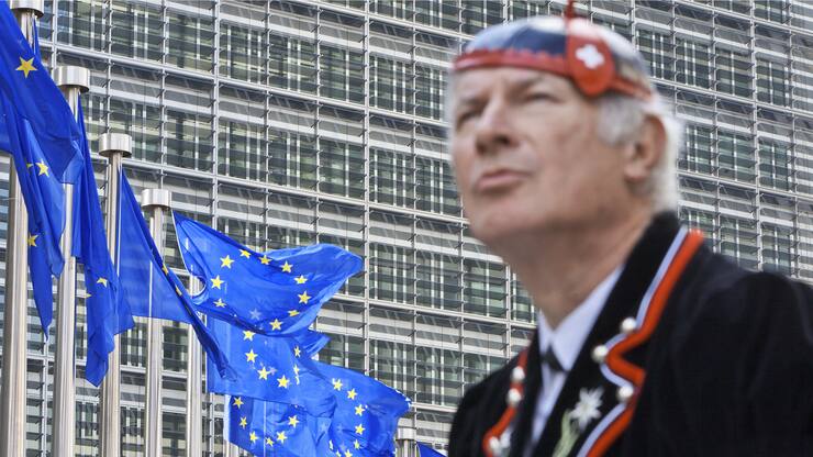 Flags of the European Union wave in front of the European Commission building in Brussels, June 8, 2011, while "Mister Swiss", dressed in a traditional Swiss costume, looks on. He is on his way to visit the heart of Europe or at least the city which hosts the headquarters of the European Union. (KEYSTONE/Martin Ruetschi) *** EDITORS NOTE: Posed picture to illustrate Switzerland within Europe. / Gestellte Aufnahme zum Thema Schweiz und Europa. ***