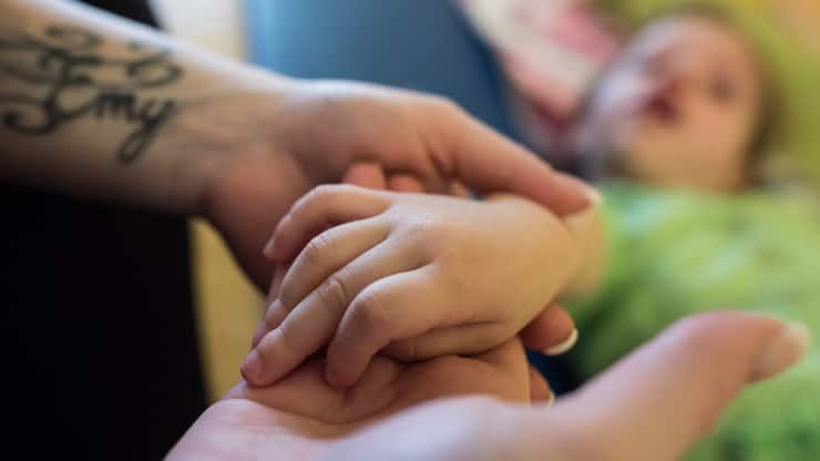 Pflegefachkraft hält die Hande eines Dreijährigen