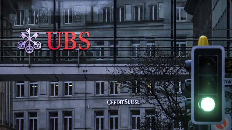 A traffic light signals green in front of the logos of the Swiss banks Credit Suisse and UBS in Zurich, Switzerland, Sunday March 19, 2023. (Michael Buholzer/Keystone via AP)