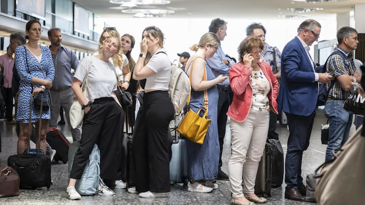 Fluggaeste warten vor einer Anzeigetafel am Mittwoch, 15. Juni 2022, auf dem Flughafen in Zuerich. Wegen einer Informatikpanne von Skyguide sind die Flughaefen Zuerich und Genf derzeit lahmgelegt. Es koennen weder Flugzeuge starten noch landen, wie eine Sprecherin in Zuerich auf Anfrage sagte. Auch Ueberfluege ueber die Schweiz sind nicht moeglich. (KEYSTONE/Ennio Leanza).