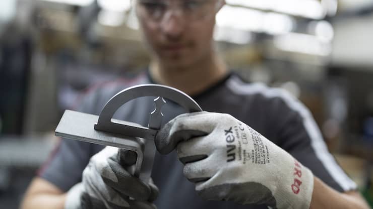 Ein Mitarbeiter von Schindler biegt mit der hydraulischen Biegemaschine und misst den Winkel eines Teils eines Schindler Lifts, fotografiert am Donnerstag, 17. Juli 2025 im Hauptsitz von Schindler in Ebikon. (KEYSTONE/Gaetan Bally)