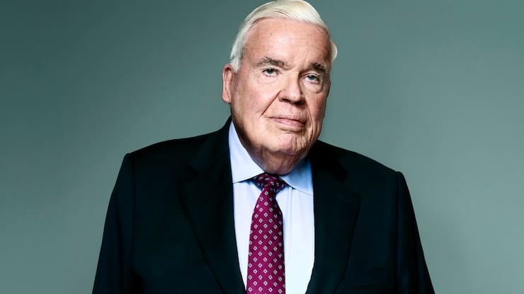 Klaus-Michael Kühne im Anzug vor dunkelgrüner Wand