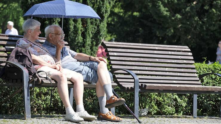 Ein älteres Paar sitzt auf einer Bank im Park.