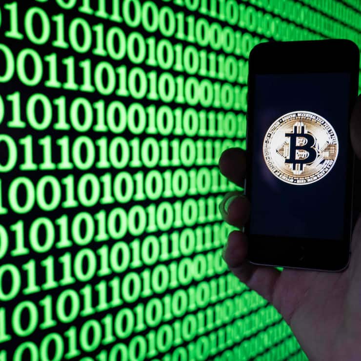 This illustration photograph shows a man holding a phone displaying a Bitcoin logo, in Mulhouse on December 5, 2025. (Photo by SEBASTIEN BOZON / AFP)