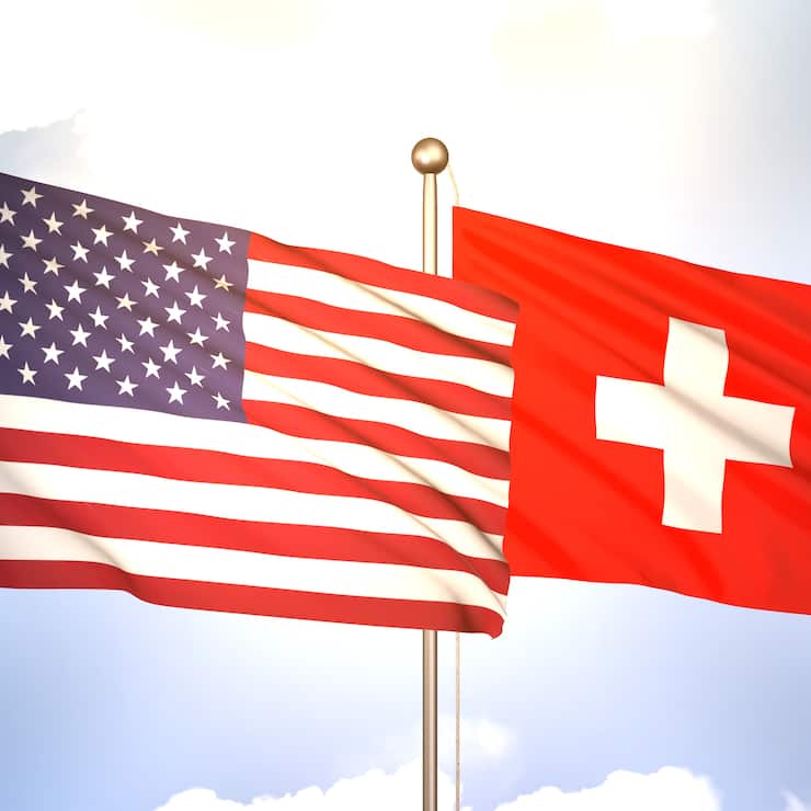 Flaggen der USA und der Schweiz wehen im Wind (2023).