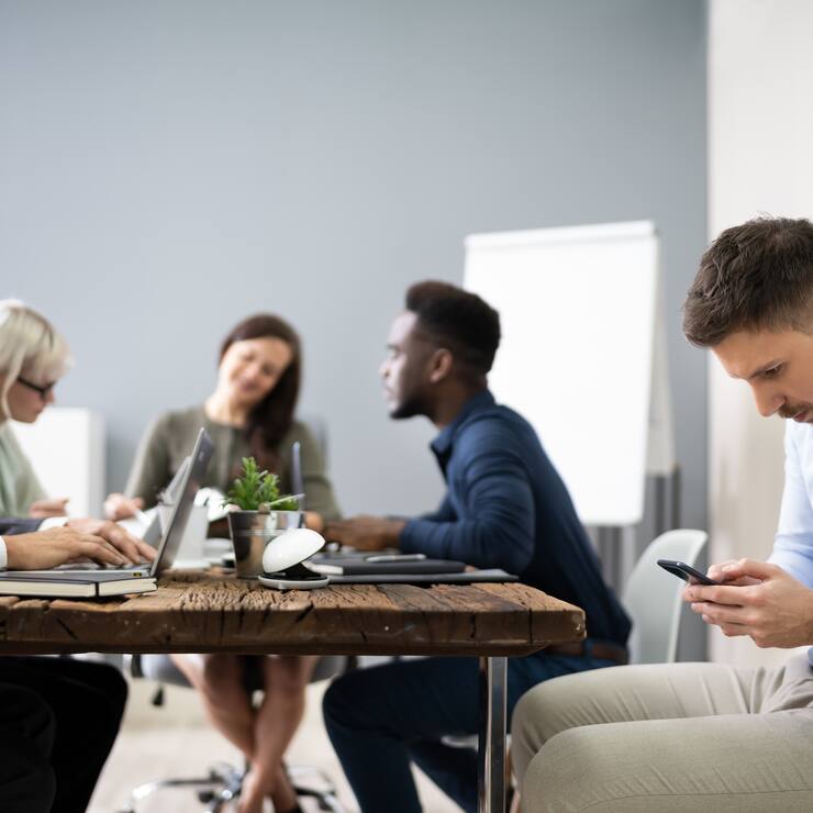 Distracted Businessman Using Mobile Phone In Meeting