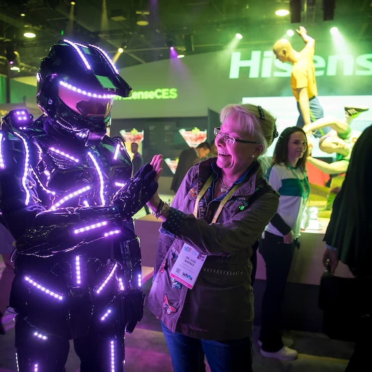 An attendee gives a high-five to a exhibitor wearing a suit with light-emitting diodes (LED) during the 2018 Consumer Electronics Show (CES) in Las Vegas, Nevada, U.S., on Thursday, Jan. 11, 2018.ÊElectric and driverless cars will remain a big part of this year's CES, as makers of high-tech cameras, batteries, and AI software vie to climb into automakers' dashboards. Photographer: David Paul Morris/Bloomberg via Getty Images