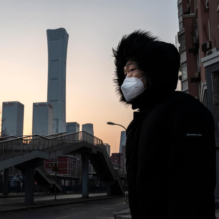 Mann in Beijing, China, vor der Skyline und trägt Maske.