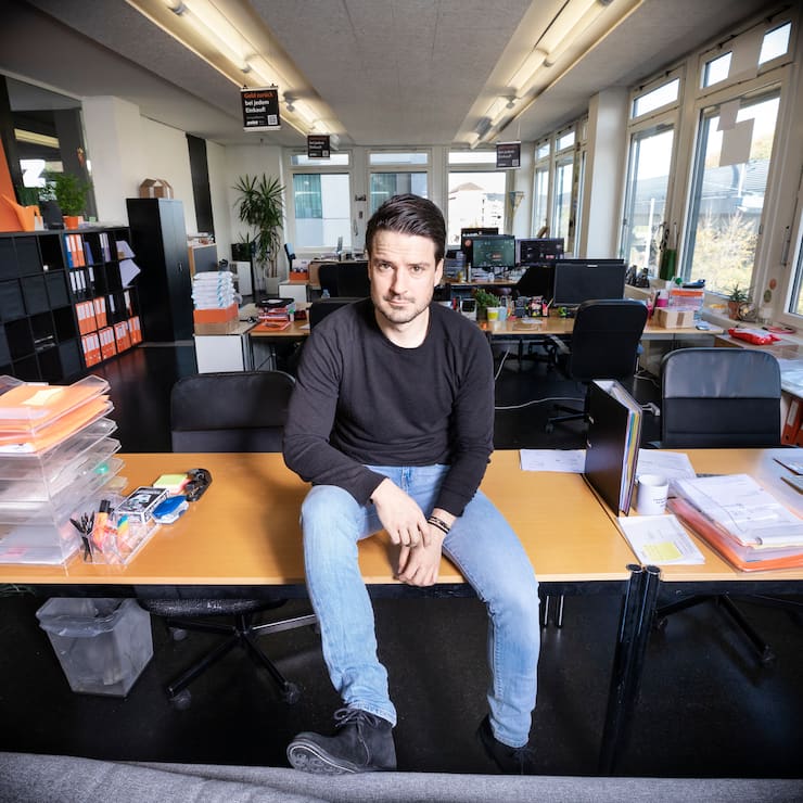 Startup Poinz, Robert Blum sitzt auf einem Tisch in seinem Büro.