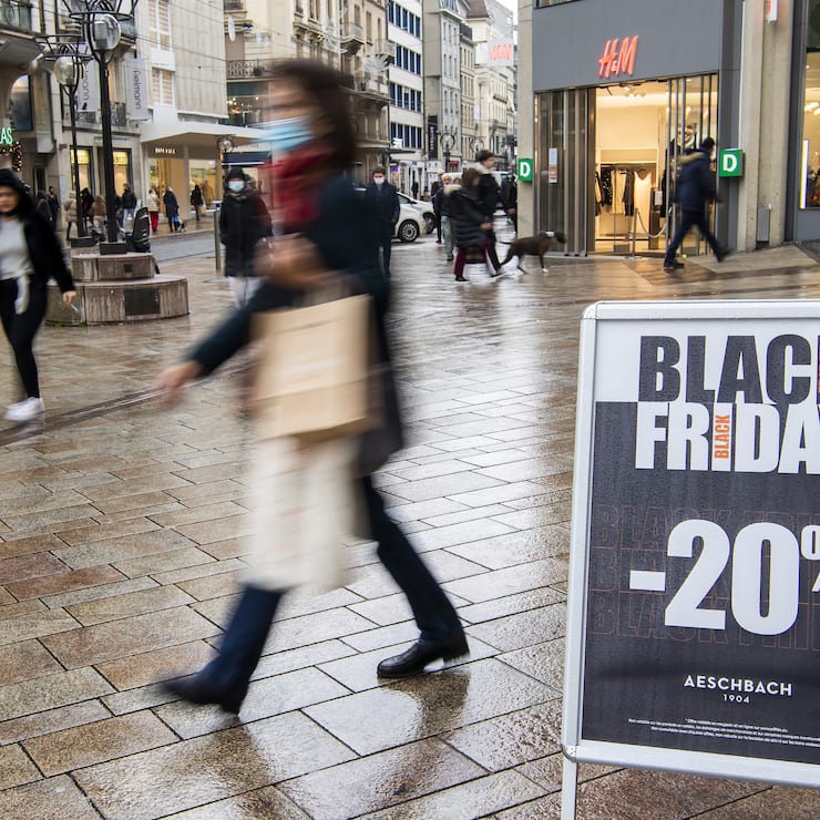 Une personne passe devant une affiche qui indique des reductions, lors de la journee Black Friday dans un magasin a Geneve, ce vendredi 26 novembre 2021. (KEYSTONE/Martial Trezzini)