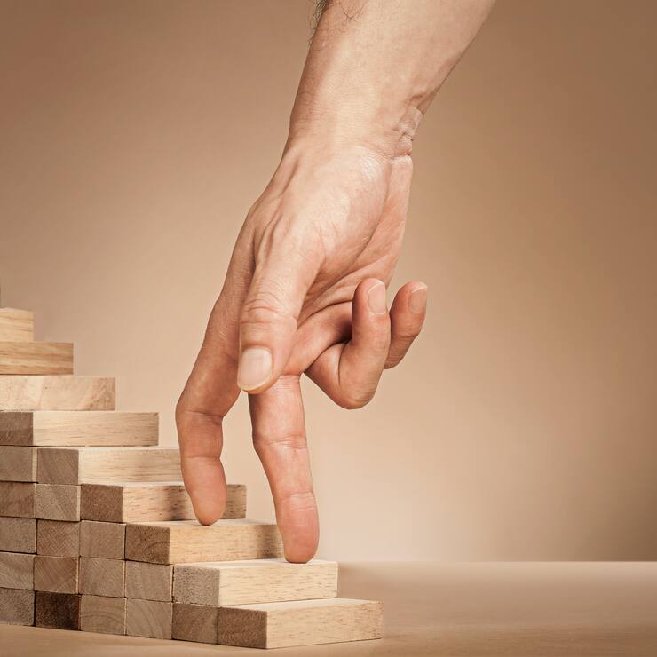 Eine Hand fährt über eine kleine Holztreppe