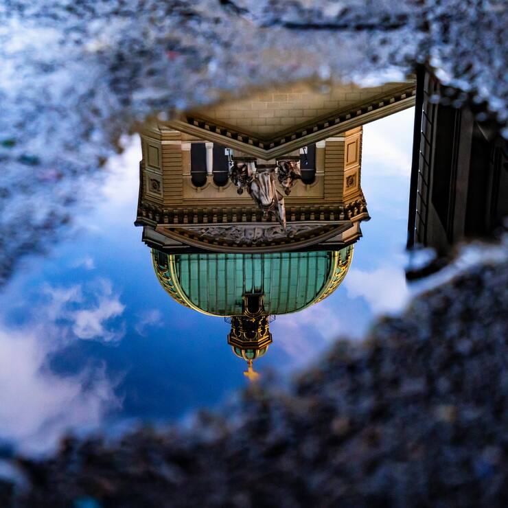 Das Bundeshaus in Bern spiegelt sich nach dem Regen in einer Pfütze.