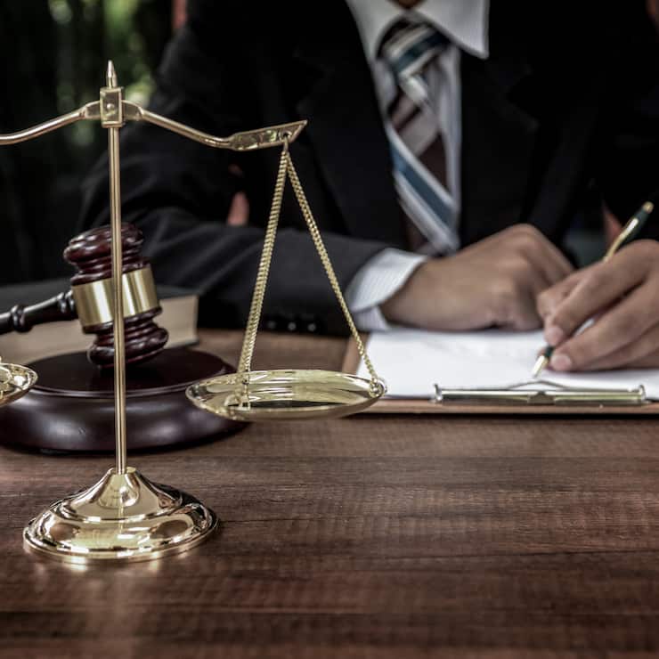 Tribunal attorney lawyer working with documents and wooden judge gavel on table in courtroom.