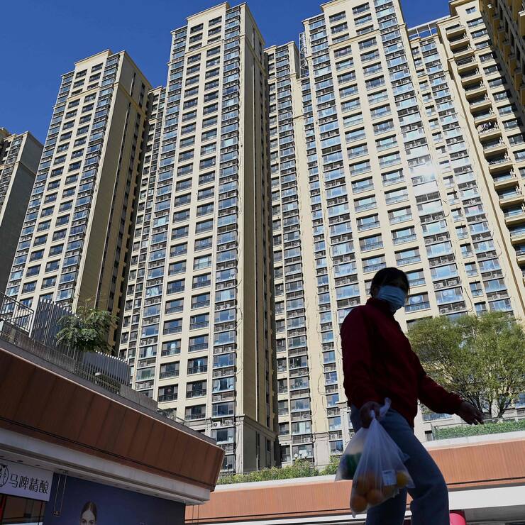 A woman walks in front of a housing complex by Chinese property developer Evergrande in Beijing on October 21, 2021. (Photo by Noel Celis / AFP)