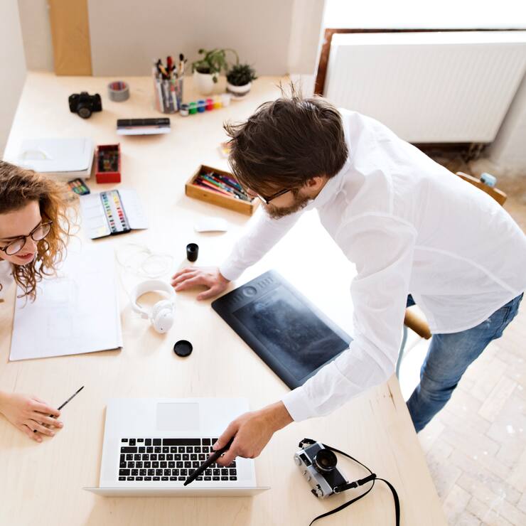 Two young architects with laptop consulting a project together. Designers and team workers in creative office.