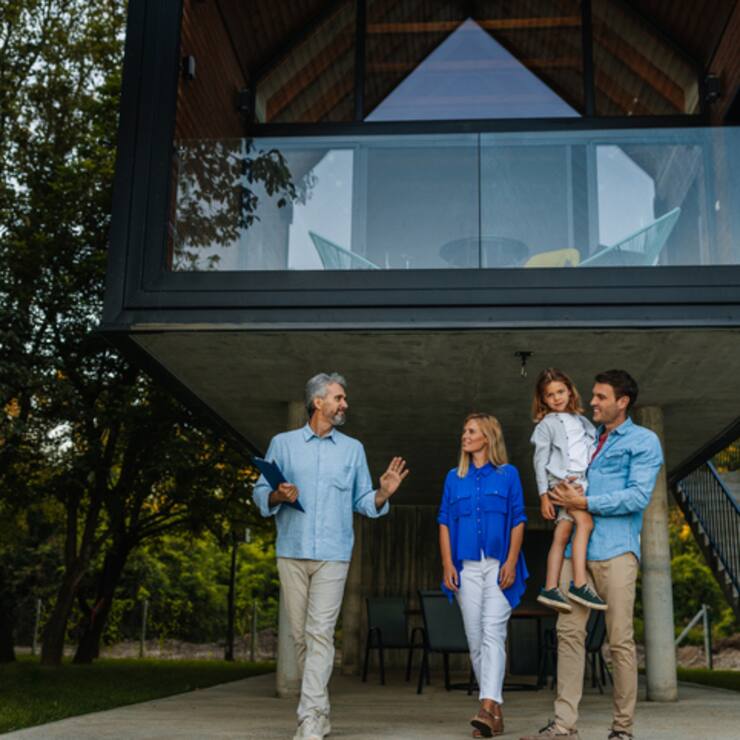 Family standing outside of their new home with their real estate agent