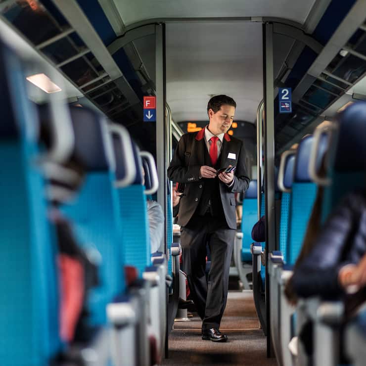 A train conductor of the Swiss Federal Railways checks passenger's tickets on a train travelling from Zurich to Lucerne, Switzerland, on March 20, 2017. (KEYSTONE/Christian Beutler)