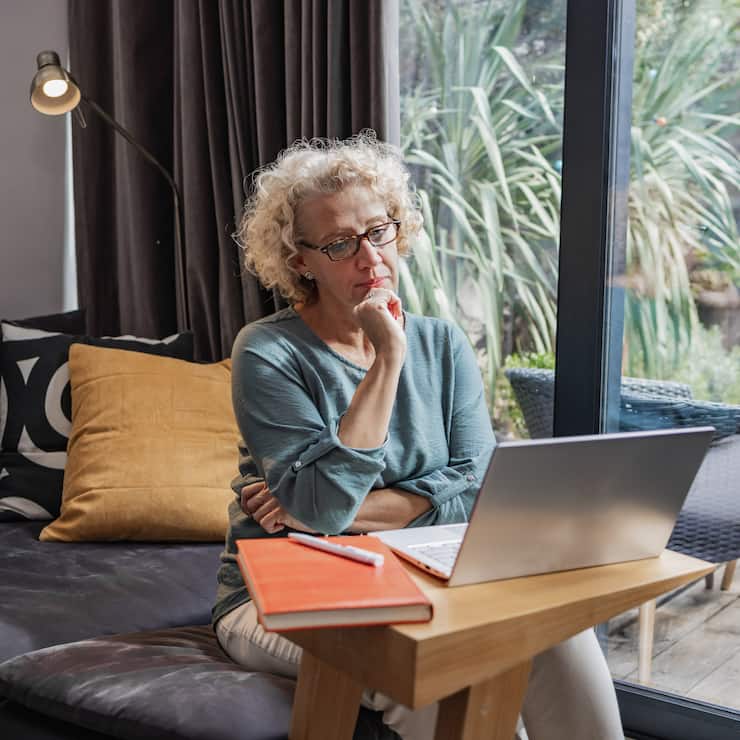 Mature woman with eyeglasses, remote working. Small business owner working from home in a modern apartment.