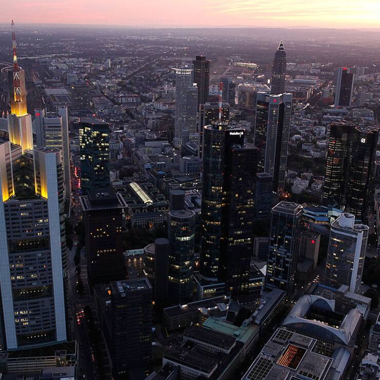The headquarters of Commerzbank (L) and the twin towers of Deutsche Bank (R) stand illuminated amid the skyline 