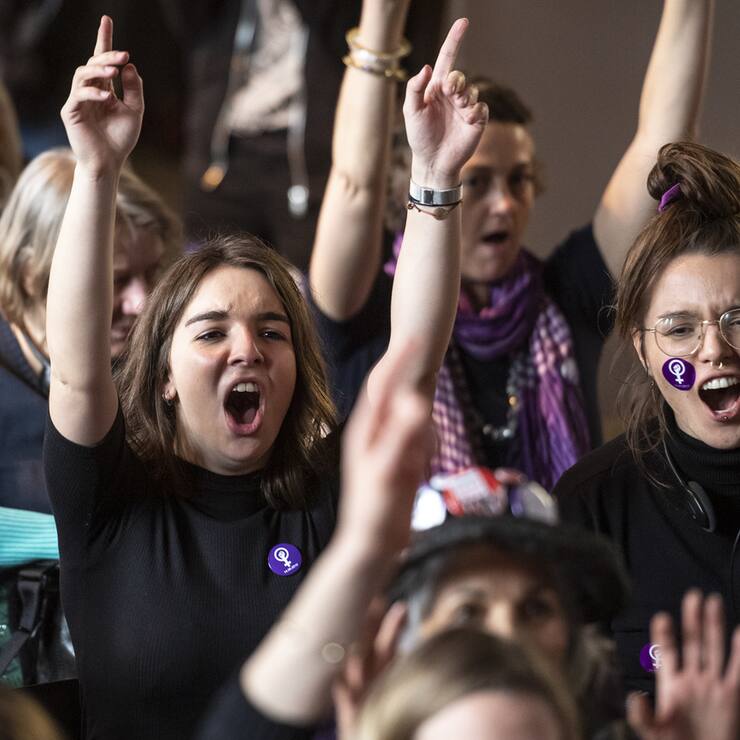 Des femmes font le signe du feminisme avec les mains, et brandissent des pancartes, lors d'une action collective organisee durant les Assises nationales pour la greve feministes et des femmes, ce dimanche 10 mars 2019 a la Maison du Peuple, a Bienne. (KEYSTONE/Adrien Perritaz)