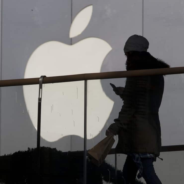 A woman using a phone walks past Apple's logo near its retail outlet in Beijing Monday, Dec. 23, 2013. Apple and China Mobile announced a long-anticipated agreement Monday to bring the iPhone to the world's biggest phone company. The iPhone, once hugely popular in China, has been eclipsed by the rise of lower-priced rival smartphones from Samsung and Chinese companies. (AP Photo/Ng Han Guan)