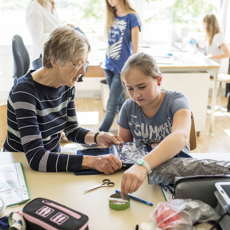 Eine Rentnerin hilft Primarschuelern freiwillig beim Textilunterricht, anlaesslich des Projektes win3, drei Generationen im Klassenzimmer, von Pro Senectute, in Schliern, am 24. Juni 2015. (KEYSTONE/Christian Beutler)