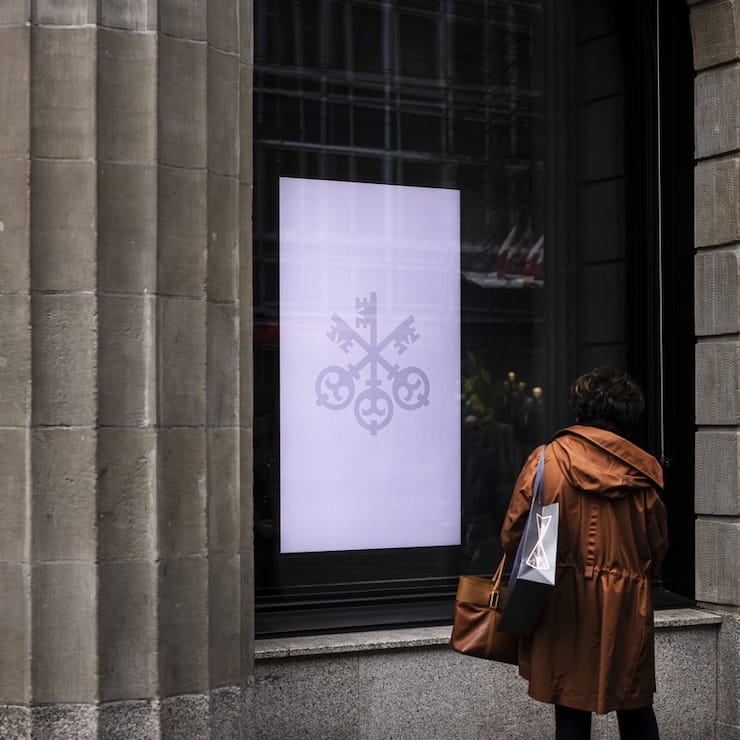 A woman looks at a screen at the entrance of the headquarters of the Swiss bank UBS in Zurich, Switzerland, on Friday, March 24, 2023. (KEYSTONE/Michael Buholzer).