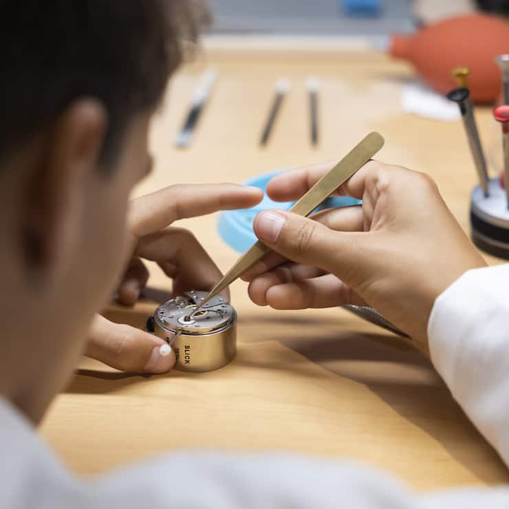 Ein junger Mann uebt bei einem Stand der Uhrmacher mit einer Pinzette und einem Uhrwerk, bei den Schweizer Berufsmeisterschaften SwissSkills 2022, am Freitag, 9. September 2022, in Bern. (KEYSTONE/Peter Klaunzer)