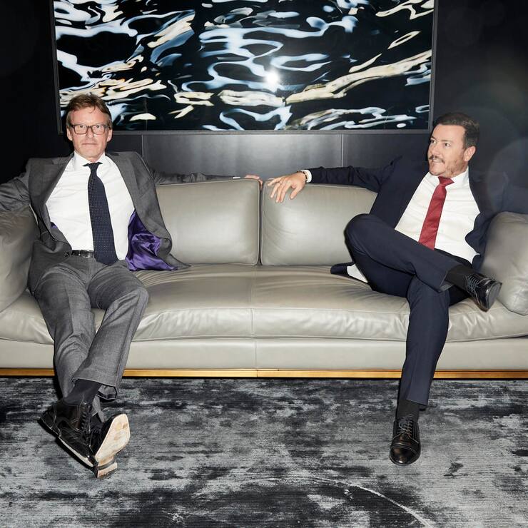 Porträt von René Benko und Dieter Berninghaus auf einem hellen Sofa.