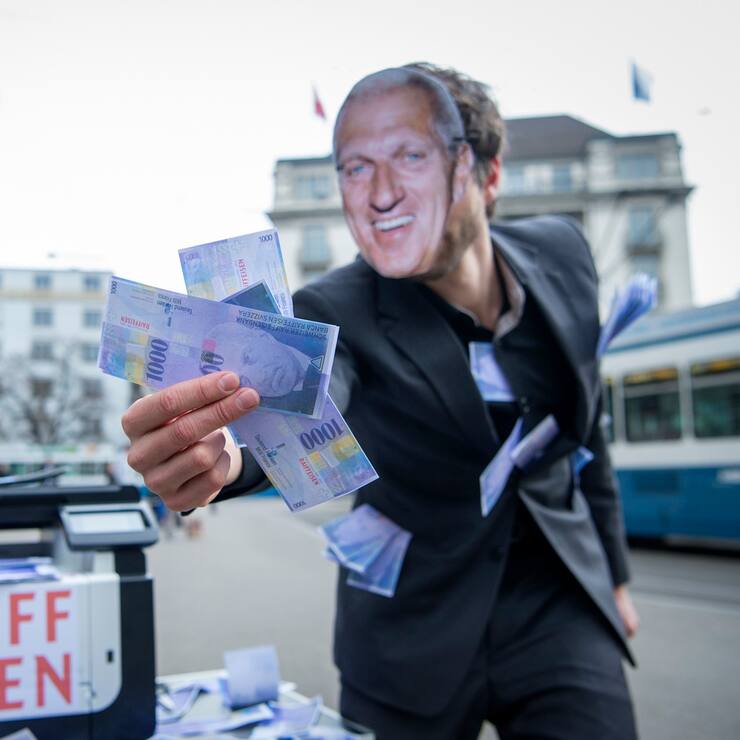 Ein Vollgeld-Aktivist mit einer Pierin Vincenz-Maske hält gedruckte Tausender Noten in der Hand