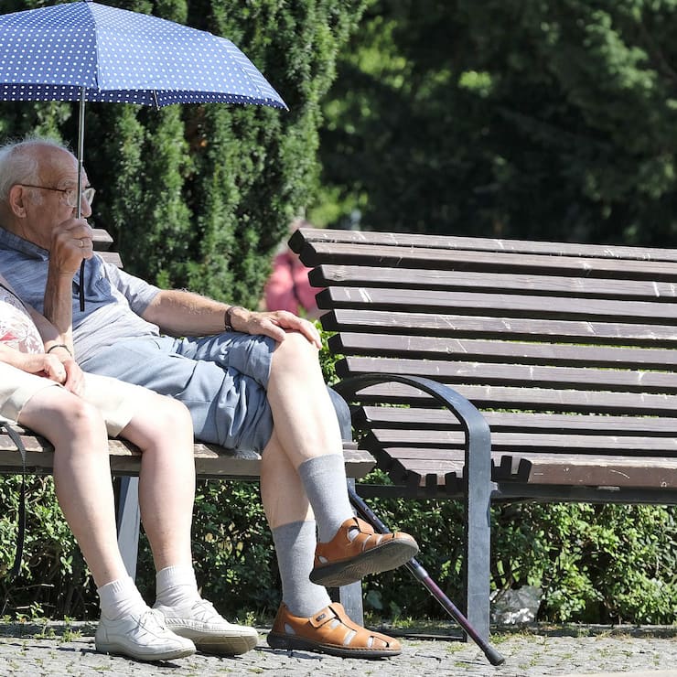 Ein älteres Paar sitzt auf einer Bank im Park.