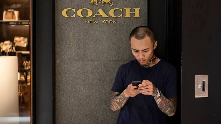 Junger Mann vor dem Laden der amerikanischen Luxusmarke Coach in Hongkong.