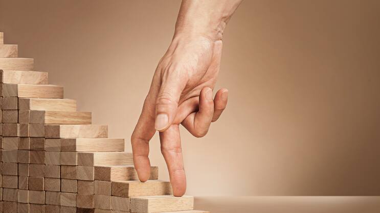 Eine Hand fährt über eine kleine Holztreppe