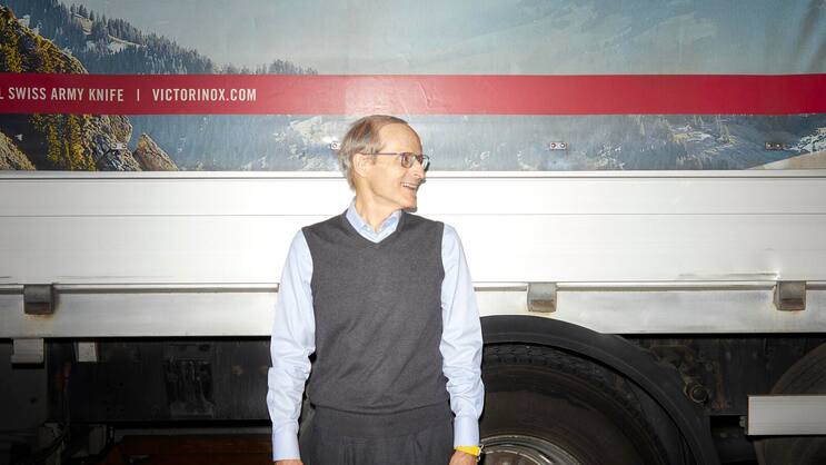 Carl Elsener vor einem Lastwagen blickt nach rechts.