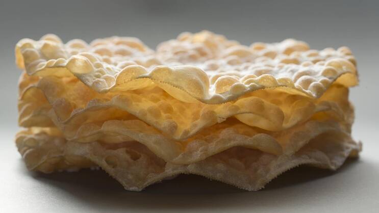 Die Blasen erhält der Teig durch das Ausrollen mit einem Nadelholz vor dem Frittieren.