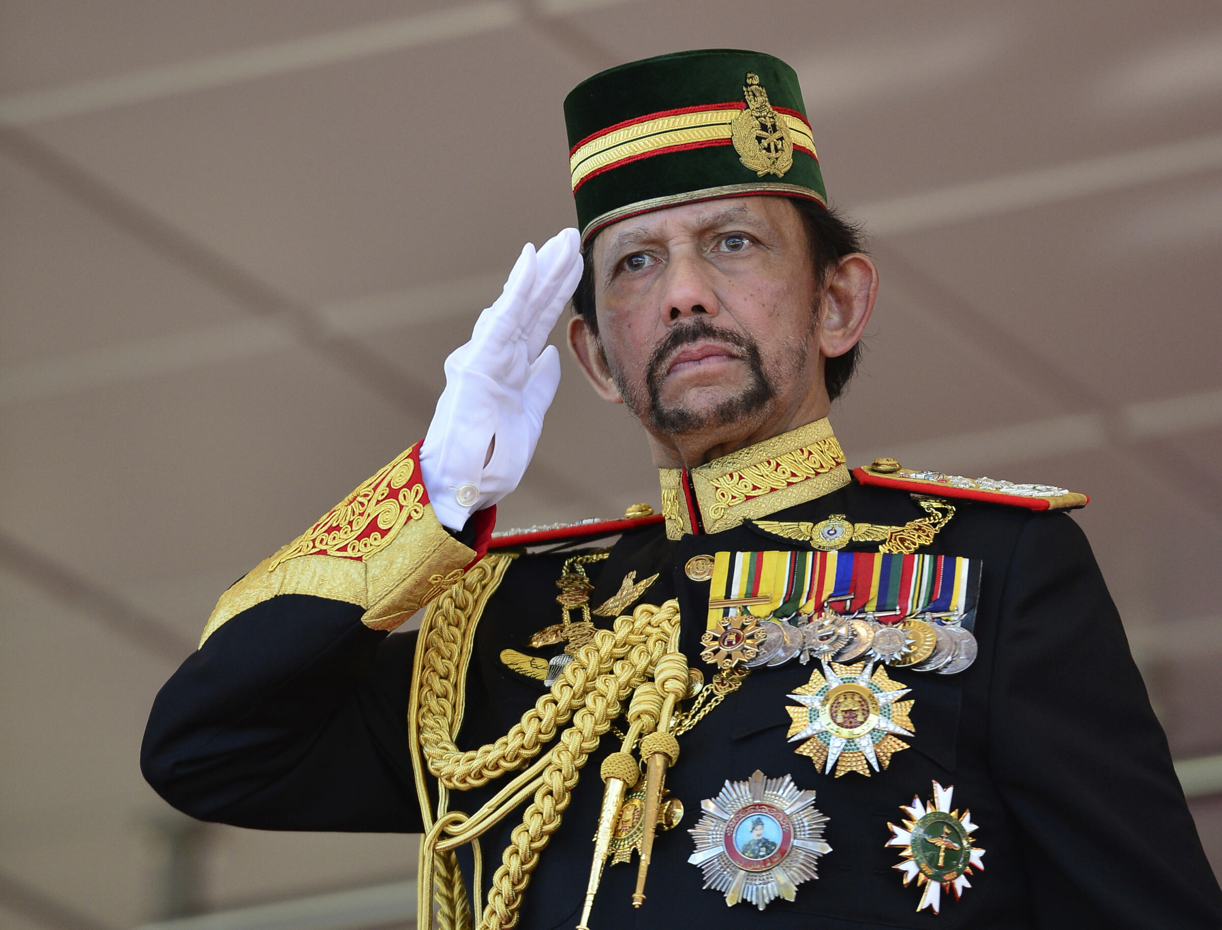 Brunei's Sultan Hassanal Bolkiah dressed in full military regalia salutes to an honor guard during his 73rd birthday celebrations in Bandar Seri Begawan, Brunei, Monday, July 15, 2019. (AP Photo/Ahim Rani)