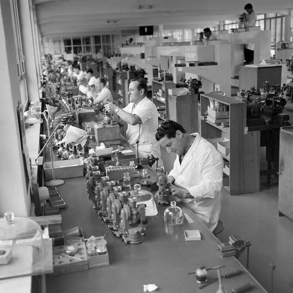 Mitarbeiter der Firma Wild Heerbrugg AG, Hersteller optischer Vermessungsinstrumente, Labor- und Stereo-Mikroskopen, Reisszeugen und Instrumenten fuer die Photogrammetrie, aufgenommen im Kanton St.Gallen am 9. November 1960. Die von der Montage vormontierten Wild-Theodolithen (vorne T16, hinten T29) werden von den Justierern in 10er-Serien fertig justiert. (KEYSTONE/PHOTOPRESS-ARCHIV/Vogt)