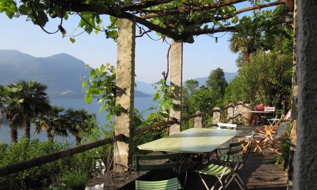 Die mit Trauben verwachsene Pergola spendet dem Sitzplatz angenehmen Schatten. Der alte Pflanzen- und Baumbestand im mediterranen Garten verleihen Authentizität.