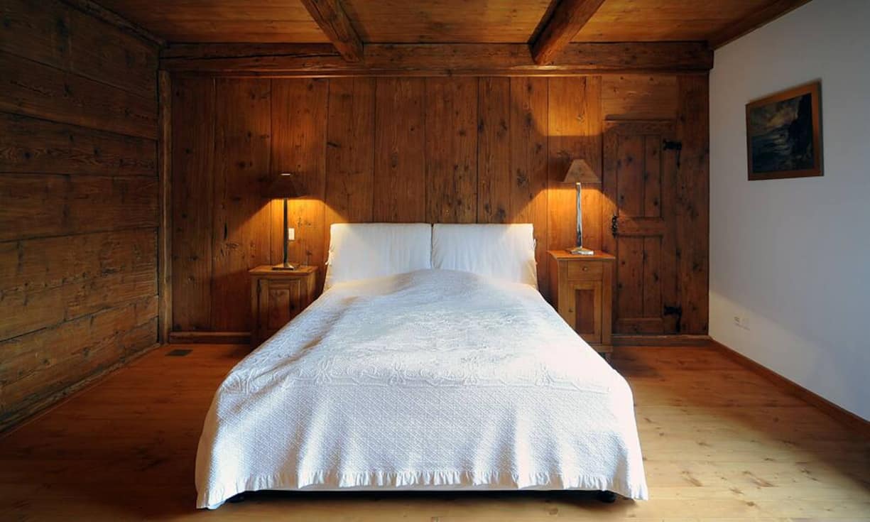 Im schlichten Schlafgemach dominieren die massiven Holzdecken und -wände und...