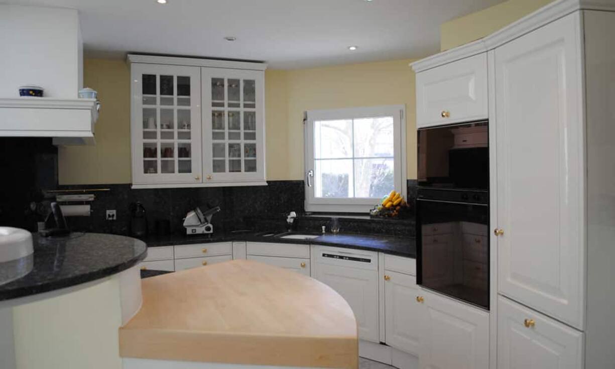 Das Entrée der Villa erstreckt sich über zwei Etagen und führt in die hochwertig ausgestatte Küche mit angeschlossenem Essbereich.