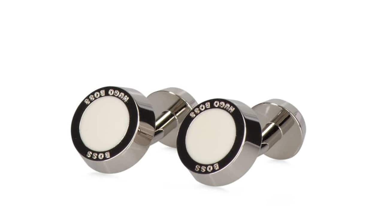 Rund: Boss Aus glänzendem Messing und mit einem Emaille-Einsatz inklusive Logo-Prägung sind diese Manschettenknöpfe von Boss gefertigt. Auch in blau und schwarz erhältlich. Preis 99 Franken