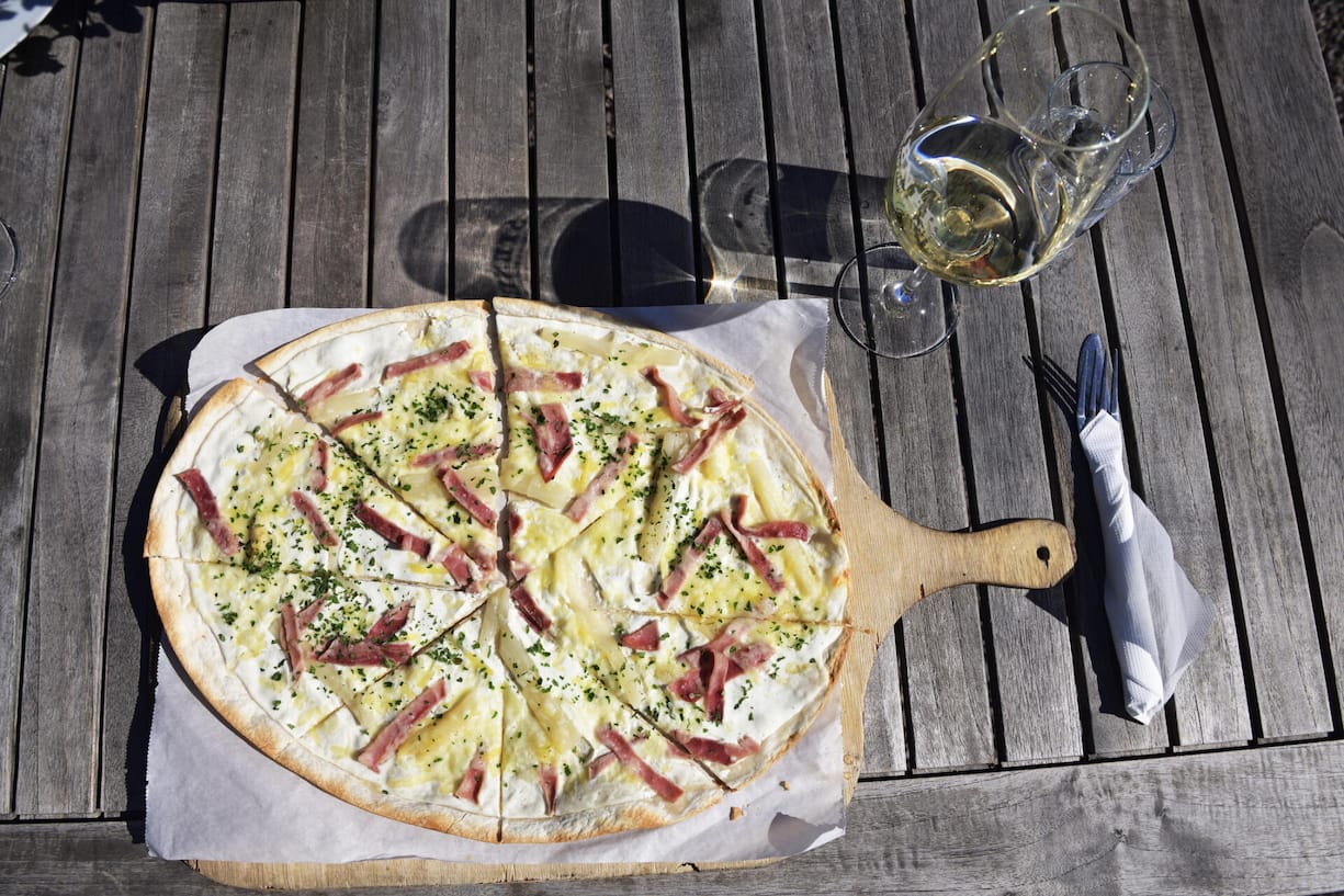 Ein Flammkuchen oder ein Zvieriplättchen mit Käse und Trockenfleisch ist genau das Richtige nach einem Spaziergang durch die Reben. Dazu gehört ein leichtfüssiger, fruchtiger Weiss- oder Rotwein.