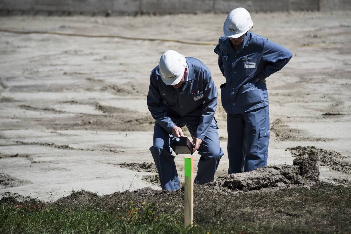 Des ouvriers de la Lonza font des mesures sur une parcelle pollue au mercure ce mercredi 6 juillet 2016 aux abords du terrain de sports Muehleye a Viege en Valais. L'entreprise Lonza, presente a la presse un projet d'assainissement pilote de parcelles contenant une pollution au mercure. (KEYSTONE/Jean-Christophe Bott)