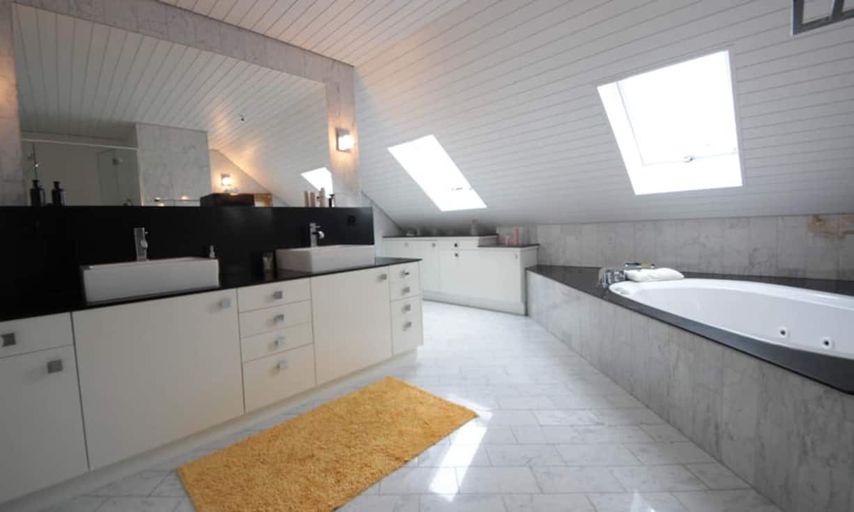 Das Badezimmer ist in hochwertigen Materialien gehalten und bietet genügend Platz zum Entspannen. Dachfenster sorgen für Tageslicht.
