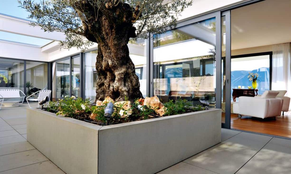 Freiplatz: Der Patio rückt den Wohnraum von der Stützmauer des Hangs ab und macht die Grenzen zwischen dem Drinnen und dem Draussen fliessend. Er ist möbliert mit Colombos Cloud Sofa und Cloud Sessel für Arflex.