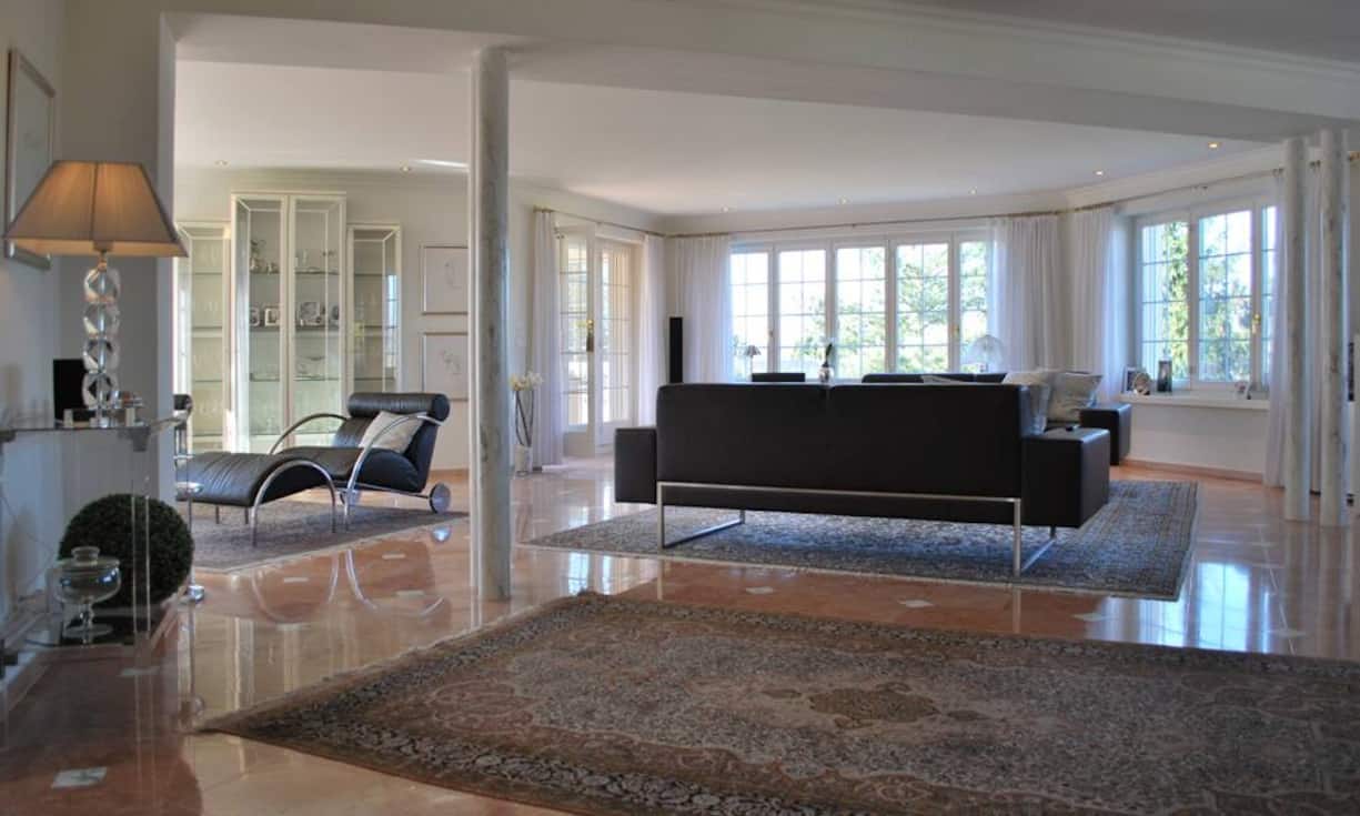 Viele Fenster und ein edler Marmboden und Säulen verleihen dem Wohnzimmer Eleganz und Luftigkeit.