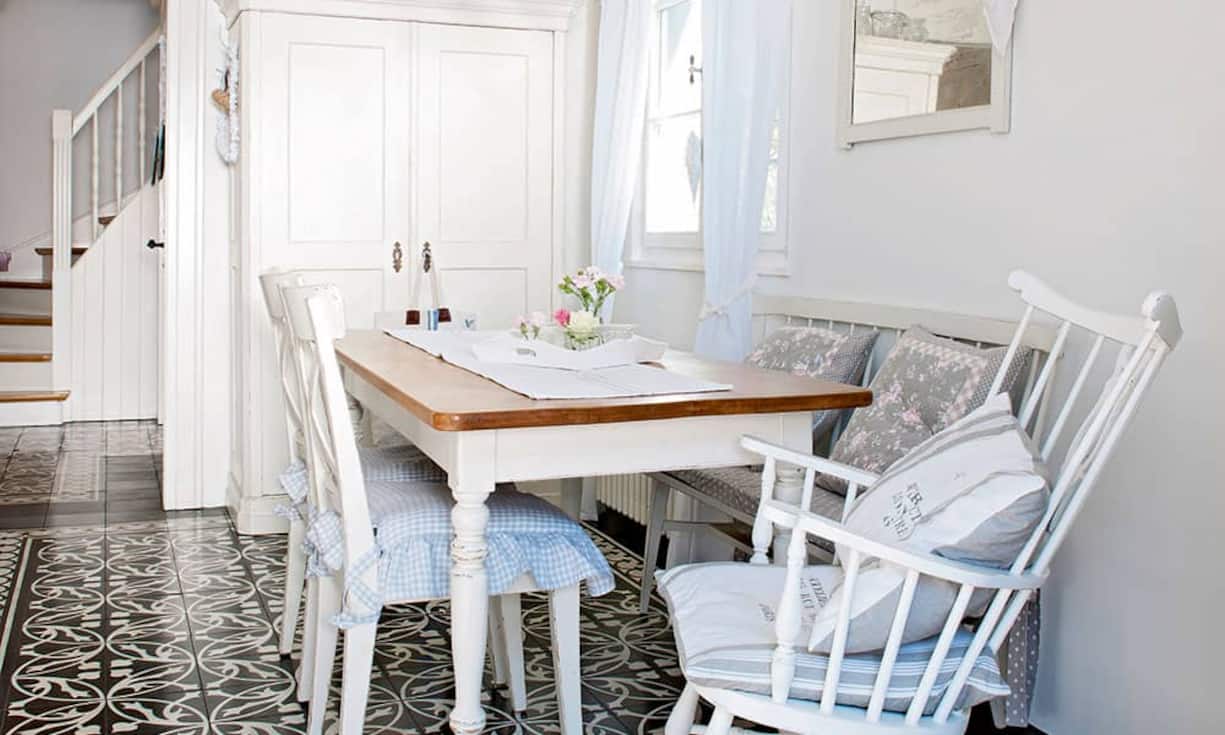 Stilfrage: Kissen und Polster mit geblümten Stoffen und ein Leuchter aus Muranoglas über dem Holztisch sind typische Stilelemente des Shabby Chic. Der Küchenboden wurde einem Jugendstilmuster nachempfunden.
