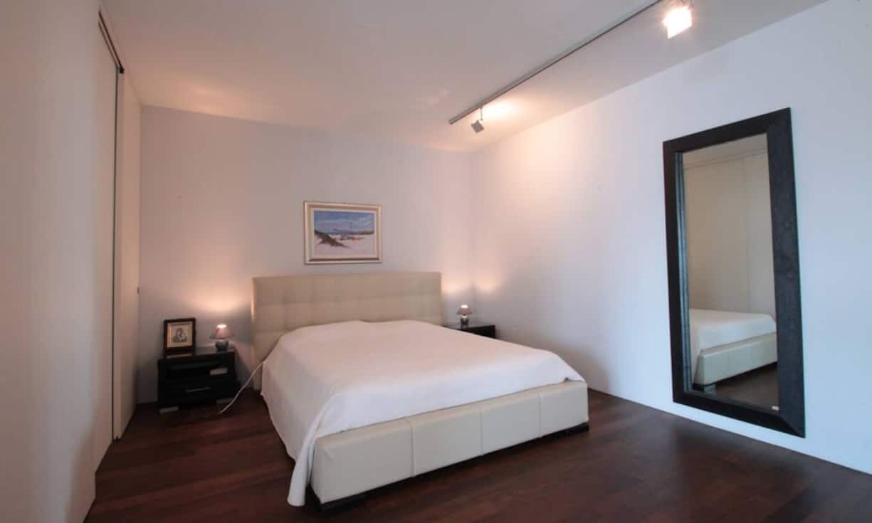 Eine vom Schreiner individuell angefertigte Ankleide mit teilweise Milchglaselementen bietet einerseits Stauraum und dient andererseits als intelligenter Raumtrenner. Schiebetüren verschwinden hierin unauffällig und bieten somit die Möglichkeit, das Schlafzimmer komplett zu schliessen oder aber in die Wohnung zu integrieren.