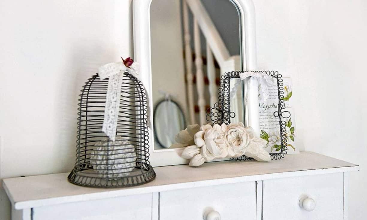 Detailliebe: Kleiner Vogelkäfig aus Draht, Spiegelchen und Blumen unterstreichen den rustikalen Chic.