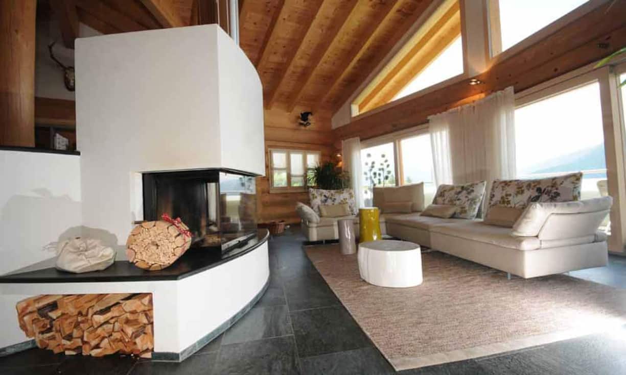 Im Wohnraum befindet sich ein grosses Cheminée. Eine grosse Fensterfront gegen Süden sorgt für helles Licht und bietet einen direkten Zugang zu den um das halbe Haus umlaufende, Balkon-Terrassen.